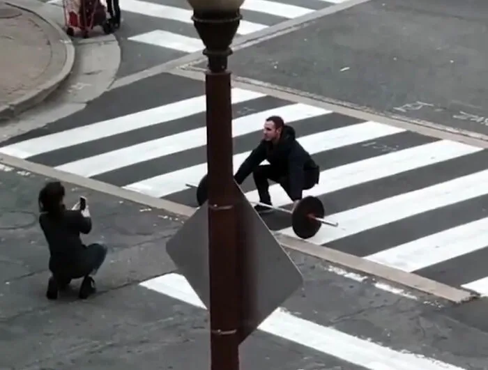 Un influencer levantando pesas en medio de la calle