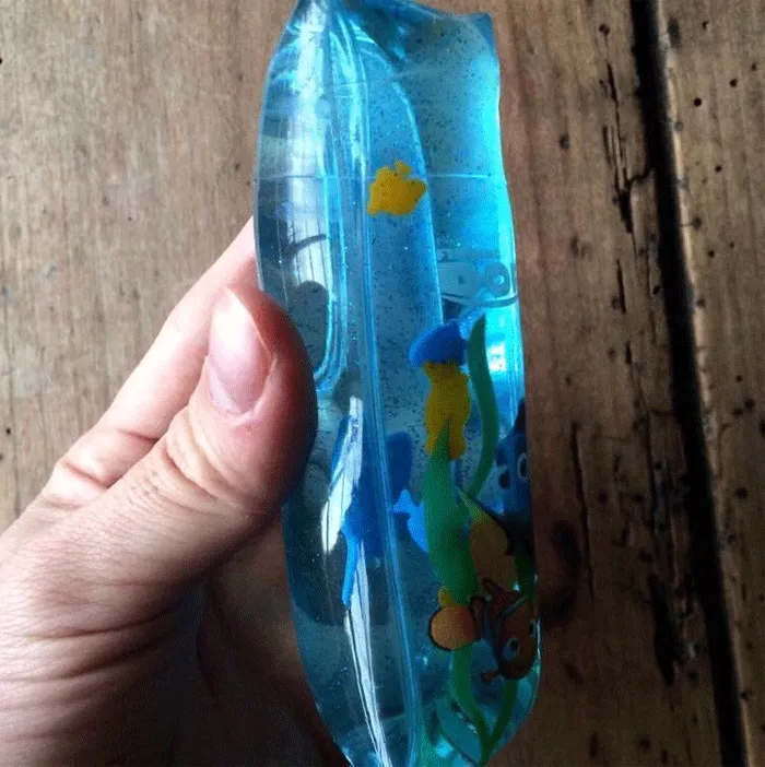 Retro squishy water toy from the '80s-'90s, hand-held, with floating shapes inside.