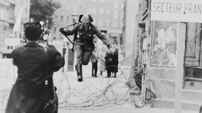 Soldier jumping over barbed wire in a historical photo, illustrating an important perspective shift during the Cold War.