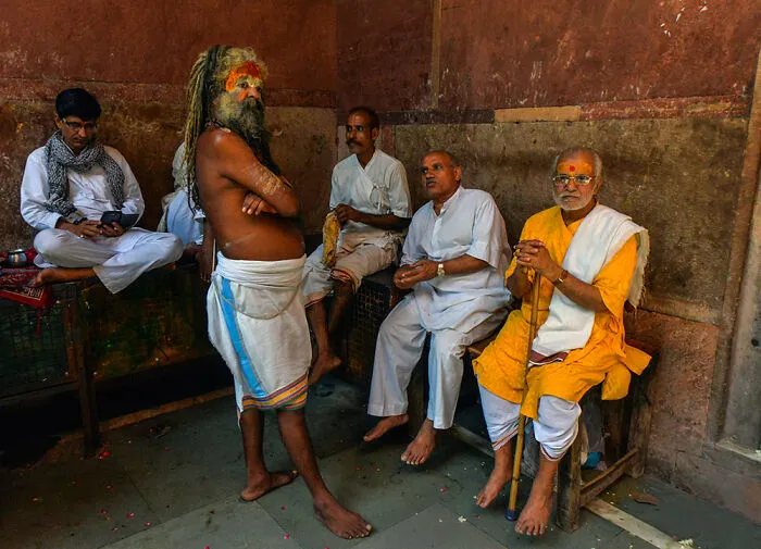 A Priest And Locals Sit Around By Robi Chakraborty
