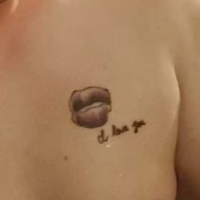 Bad tattoo featuring poorly drawn lips and illegible text on a person's skin.