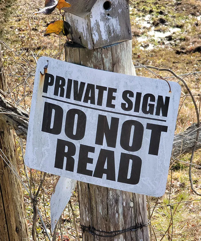 Funny sign reading "Private Sign, Do Not Read" attached to a wooden post outdoors.