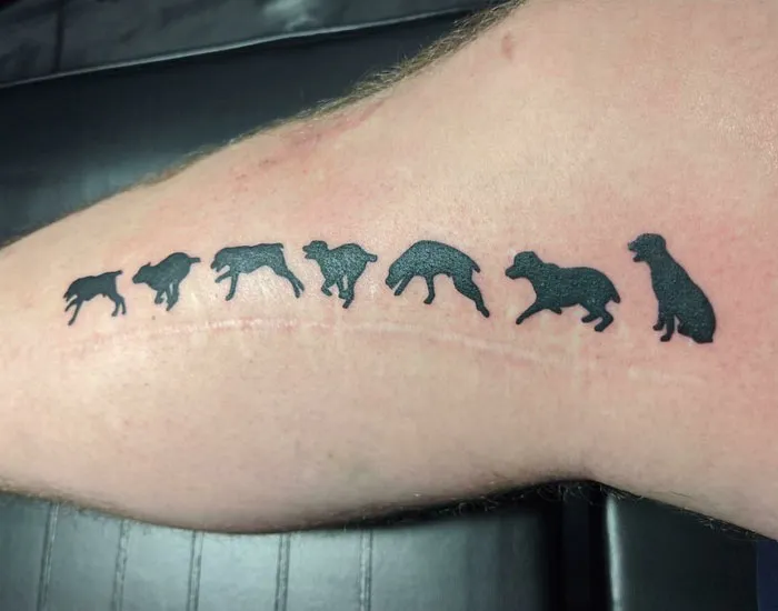 Tattoo of dog silhouettes creatively covers a scar, showcasing a skillful cover-up on a person's arm.