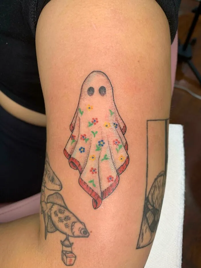 Ghost tattoo with floral sheet design on arm, showcasing a brilliantly spooky Halloween theme for horror lovers.