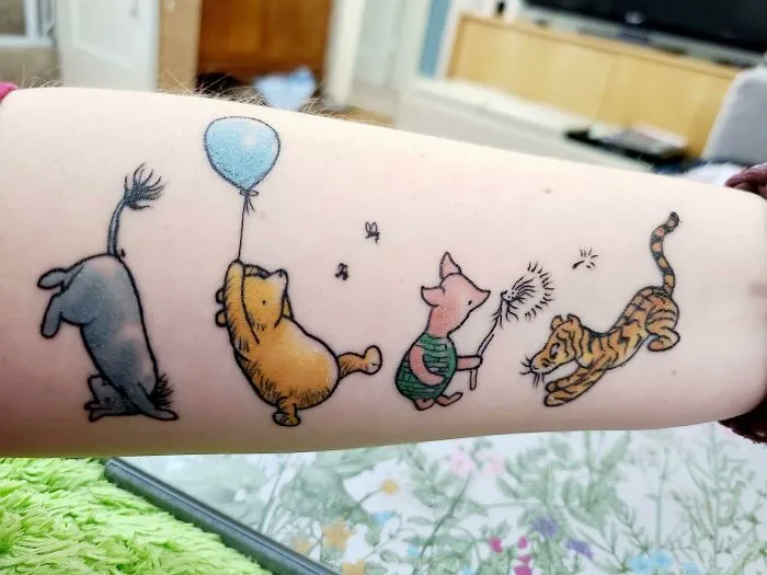 Disney tattoo of Eeyore, Pooh with a balloon, Piglet, and Tigger on an arm, illustrating interesting first tattoo ideas.