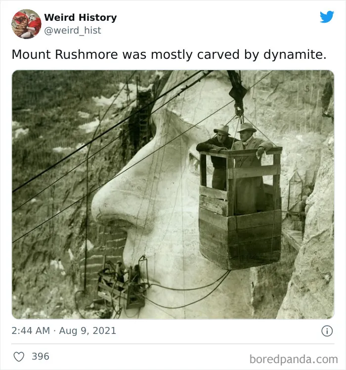 Historic black and white photo showing workers carving Mount Rushmore’s face using dynamite and suspended wooden platforms.