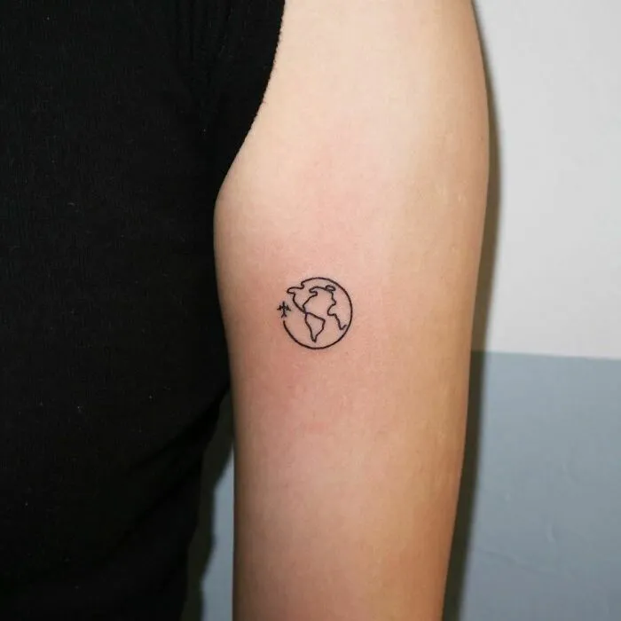 Simple first tattoo of a minimalist globe design on an arm.