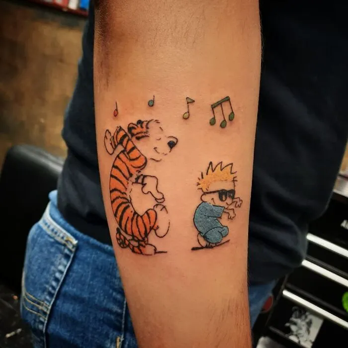 Anime characters dancing in a colorful first tattoo design with musical notes, on a person's forearm.