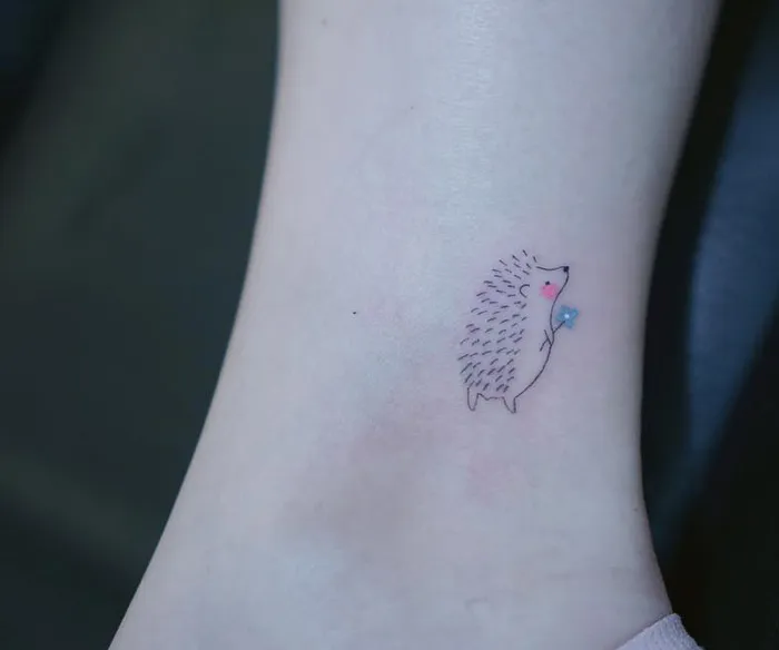 Small hedgehog tattoo on ankle, showcasing an interesting first tattoo idea.