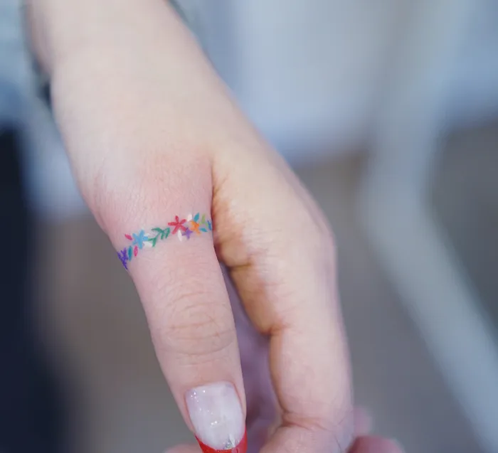 Colorful floral tattoo on a finger, showcasing an interesting first tattoo idea.