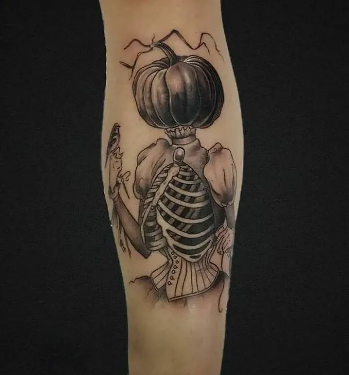 Spooky Halloween tattoo of a pumpkin-headed figure with skeletal ribcage and vintage attire.