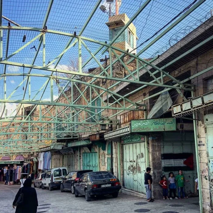 (Oc) Hebron’s Multi-Story Borders: Ground-Level Palestinians Construct Fences Above Their Streets To Protect Themselves From Upper-Story Israeli Settlers Who Throw Trash, Furniture, And Rocks Down On Them
