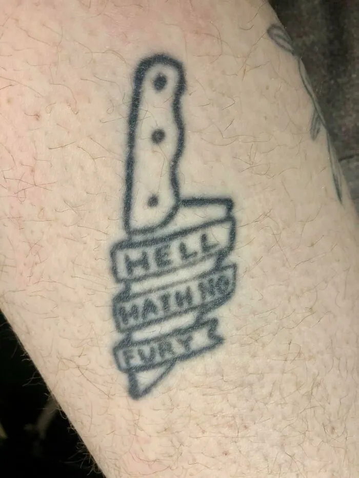 Bad tattoo of a knife with text "Hell Hath No Fury" on skin, highlighting inkshaming examples.
