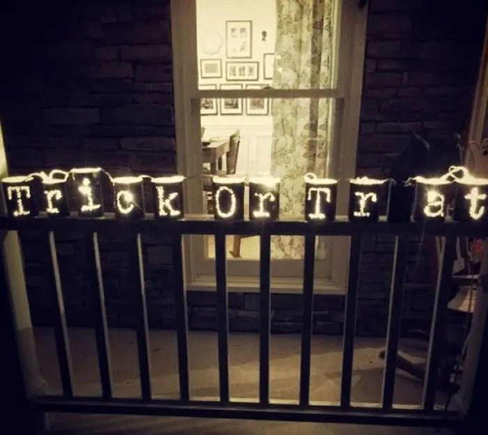Lit-up jars on a railing showing a funny Halloween fails spelling mistake Trick Or Trat.