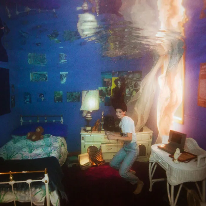 Surreal album cover with a person underwater in a bedroom setting, highlighting creative album art concepts.