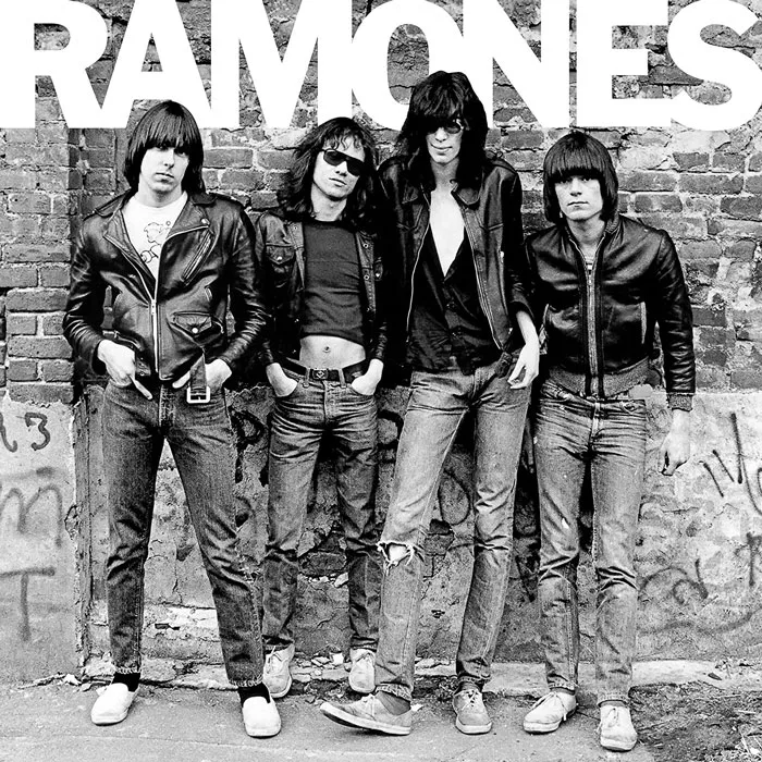 Iconic album cover of a punk band in leather jackets, standing against a graffiti-covered brick wall.