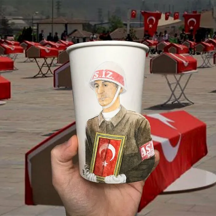 Hand holding paper cup with detailed illustration of a soldier, part of 40 illustrations drawn on paper cups while traveling.