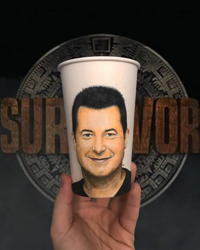 Hand holding a paper cup with a detailed portrait illustration as part of artist’s travel-themed paper cup drawings.
