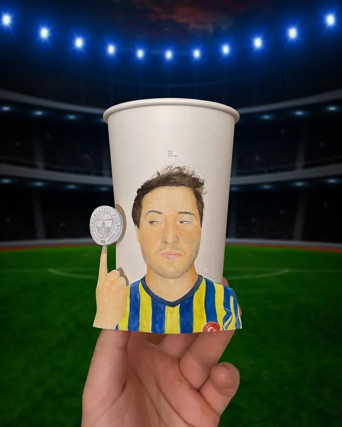 Hand holding a paper cup with detailed illustrations of a man and a coin, showcasing travel-inspired art on paper cups.