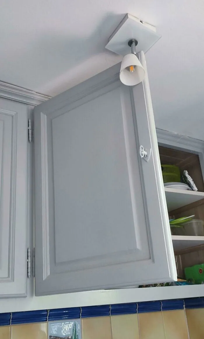 Awful interior design showing a kitchen cabinet blocking a ceiling light fixture.