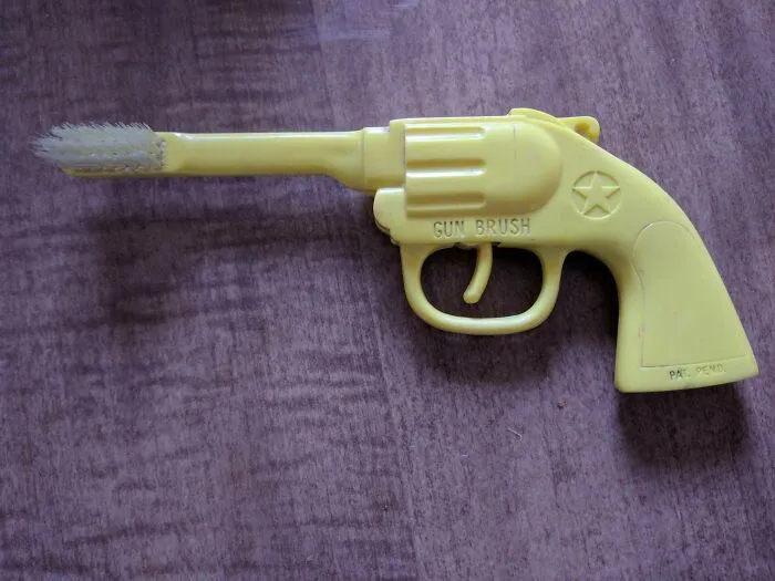 Este viejo cepillo de dientes con cerdas en el extremo del cañón de una pistola de juguete - El gatillo incluso hace clic cuando se tira