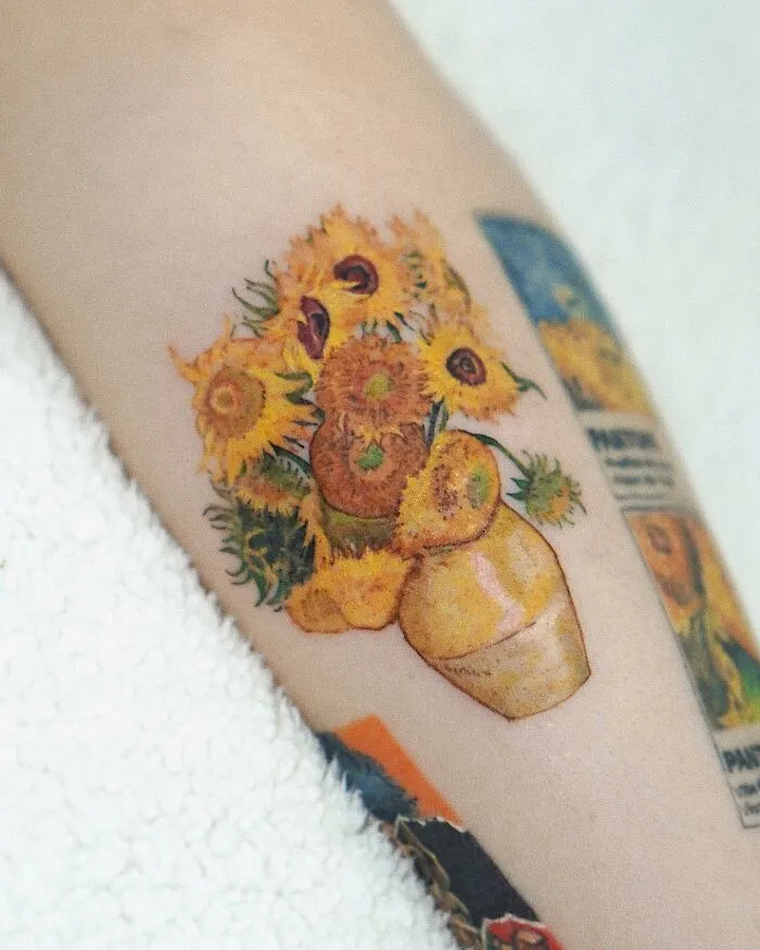 Painting-like tattoo of a sunflower bouquet on skin.