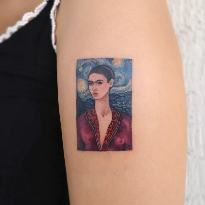 Painting-like tattoo of a woman in a vivid landscape design on an arm.