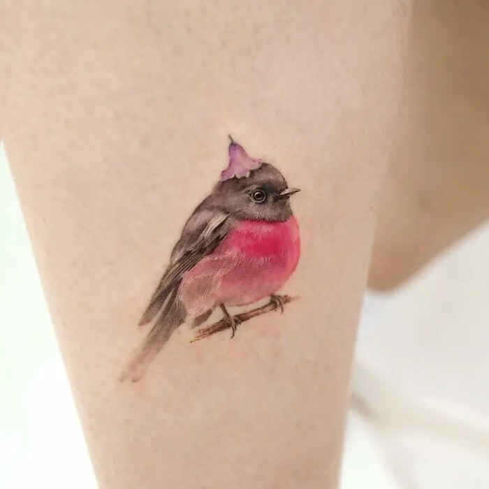 Painting-like tattoo of a colorful bird on skin, showcasing intricate artistic detail.