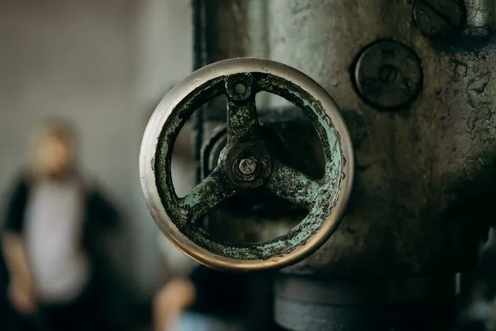 Close-up of a rusty industrial valve wheel demonstrating basic and genius safety tips for secure machinery operation.