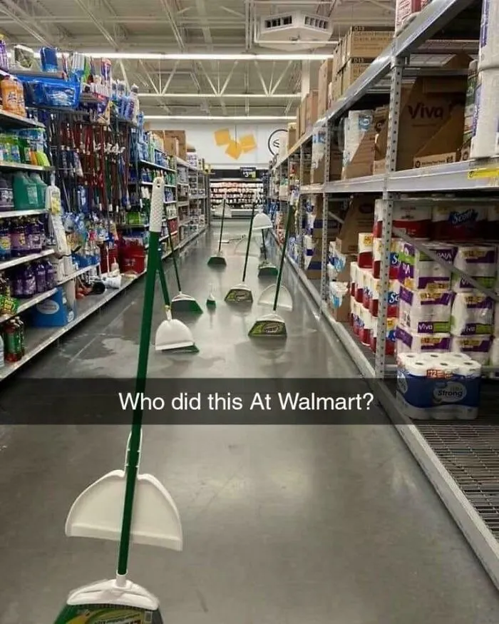 Multiple brooms with stood up in cleaning isle 