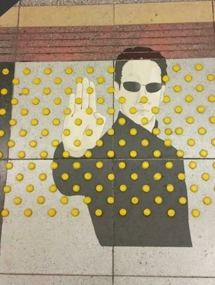 Me parece más arte que vandalismo. Neo en el pavimento táctil para invidentes