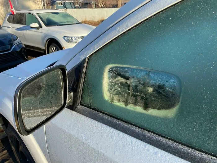 El sol que se refleja en mi espejo lateral derritió un agujero en forma de espejo en la escarcha de la ventana