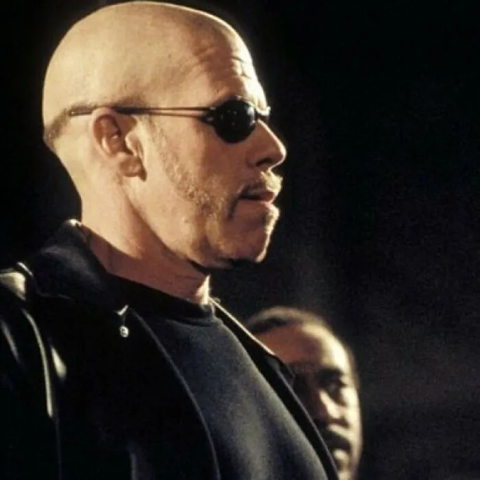 Man with a unique hairstyle wearing sunglasses and a black jacket, exemplifying worst hairstyles trend.