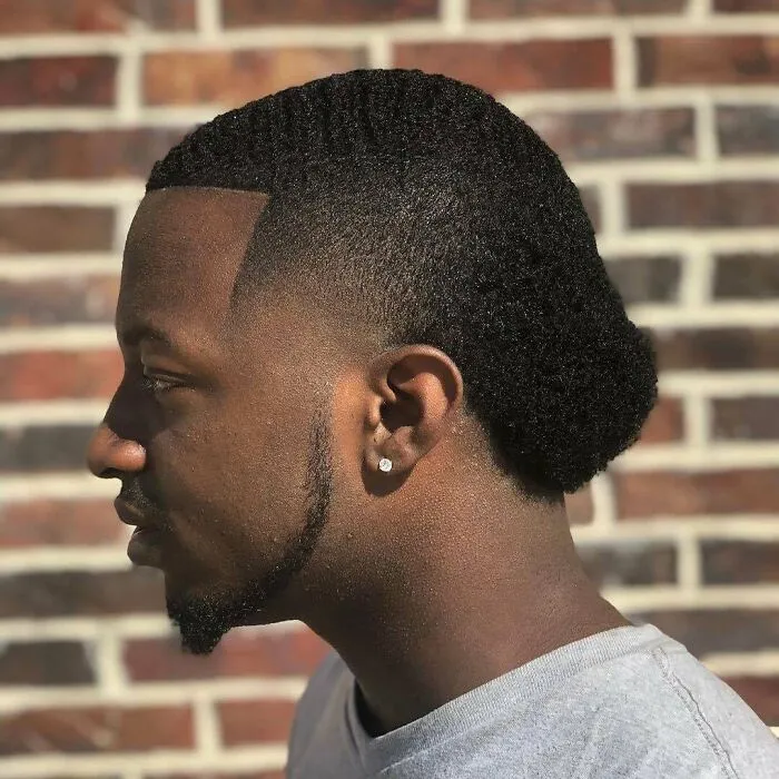 Side profile showing unusual hairstyle with a blend of sleek lines and an afro, exemplifying the worst hairstyles trend.