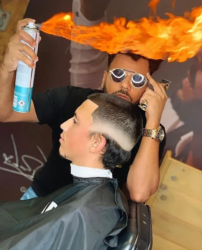 Barber creating a unique, fiery hairstyle using hairspray and sunglasses, highlighting one of the worst hairstyles online.
