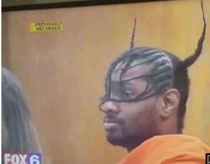 Man with unique and intricate hairstyle, braids extending towards the ceiling, showcasing an unconventional look.