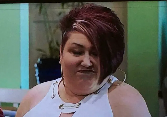 Person with an unusual hairstyle, featuring dark and light-toned sections, in a casual indoor setting.