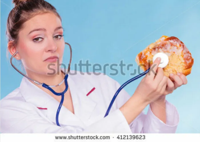 Weird stock image of a doctor using a stethoscope on a pastry against a blue background.