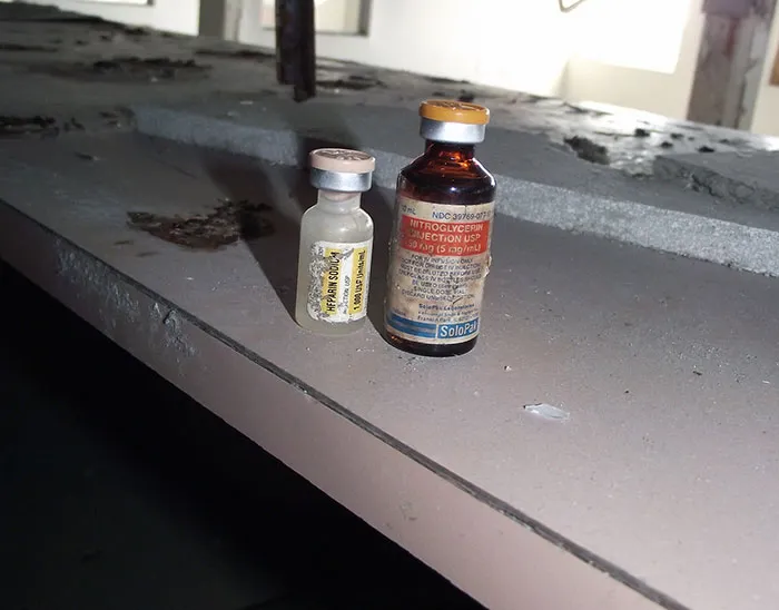 Dos frascos de medicamentos antiguos sobre una superficie polvorienta en un lugar abandonado, datos informativos curiosos.