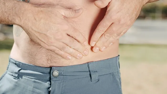 Close-up of a person showing their abdomen with hands placed on the skin, highlighting disturbing aspects of human bodies.