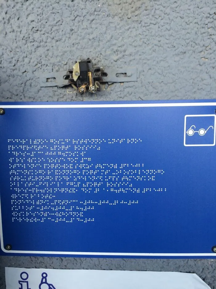 Un letrero para ciegos al lado de un cable expuesto