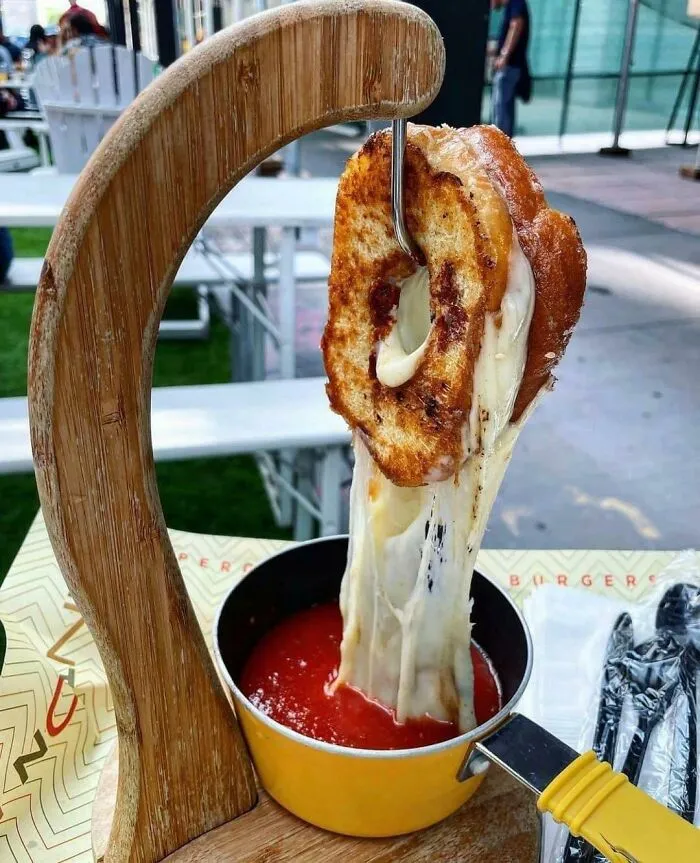 Donut glaseado con queso asado colgando sobre sopa de tomate