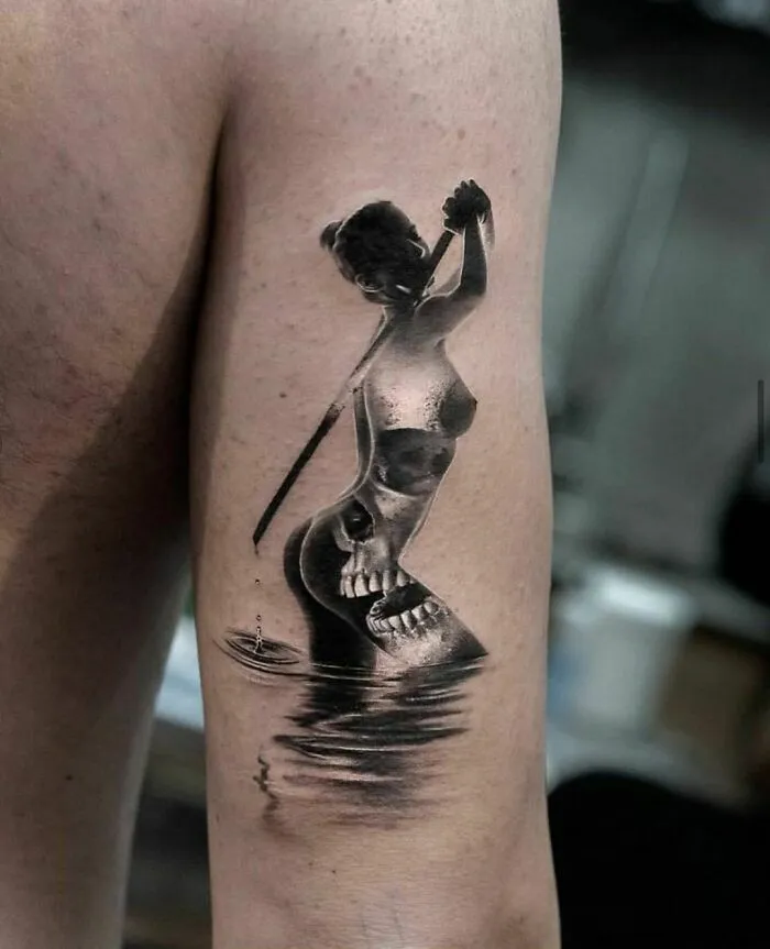 Tattoo of a mermaid and skull fusion on an arm, showcasing creative ink art.