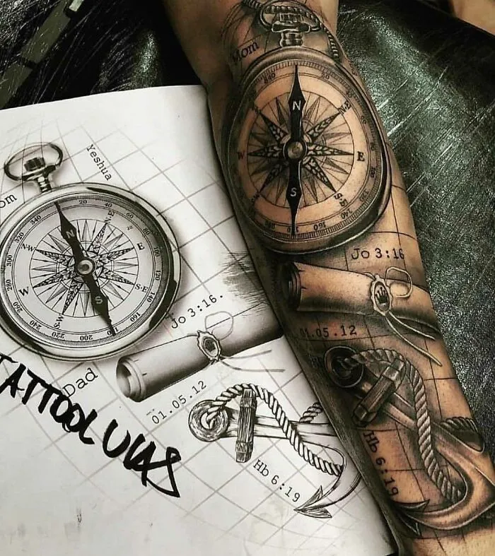 Detailed compass tattoo on arm beside sketchbook showing intricate ink designs.