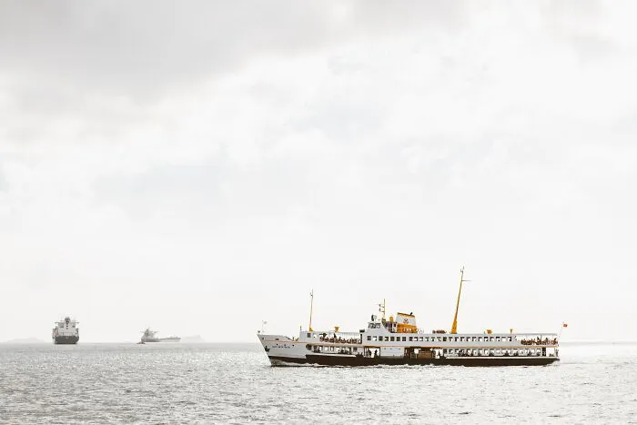Passenger ferry and cargo ships on a calm ocean under a cloudy sky, illustrating creepy facts about the ocean.