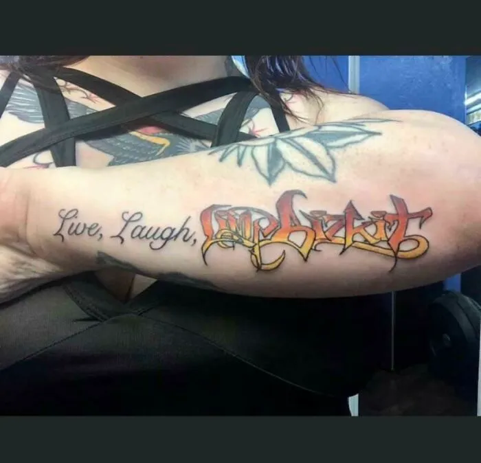 Close-up of a tattoo on an arm with "Live, Laugh" and intricate lettering, illustrating bad tattoo designs.