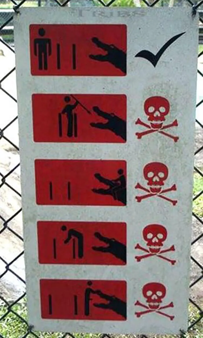 Funny sign showing do's and don'ts with crocodile, warning of danger with illustrations and skull icons.