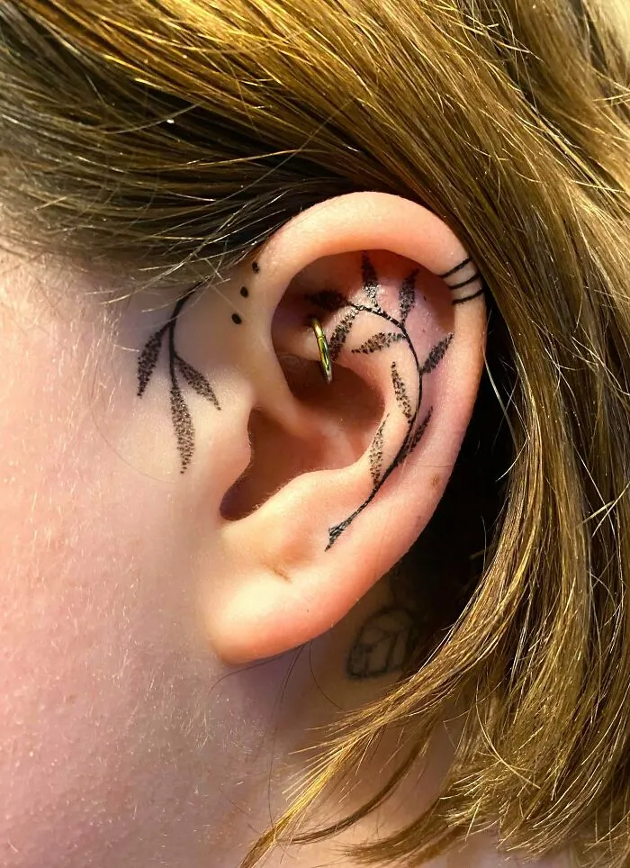 Ear tattoo with leaf design on a person's ear, showcasing subtle tattoo art.