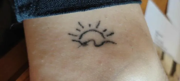 Simple sun tattoo on skin, showcasing latest body art design.