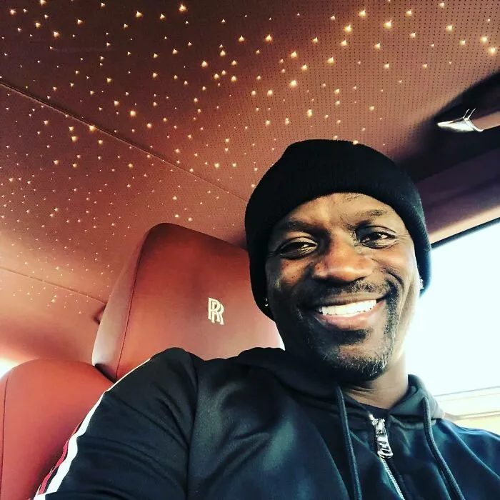 Smiling man inside luxurious car with star-lit ceiling, symbolizing celebrity wealth.